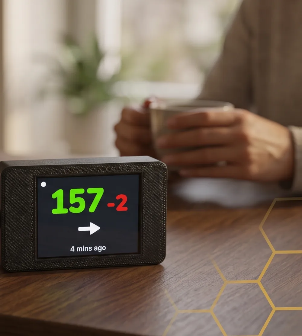 SugrBee on a kitchen table while someone holds a cup of coffee in the background